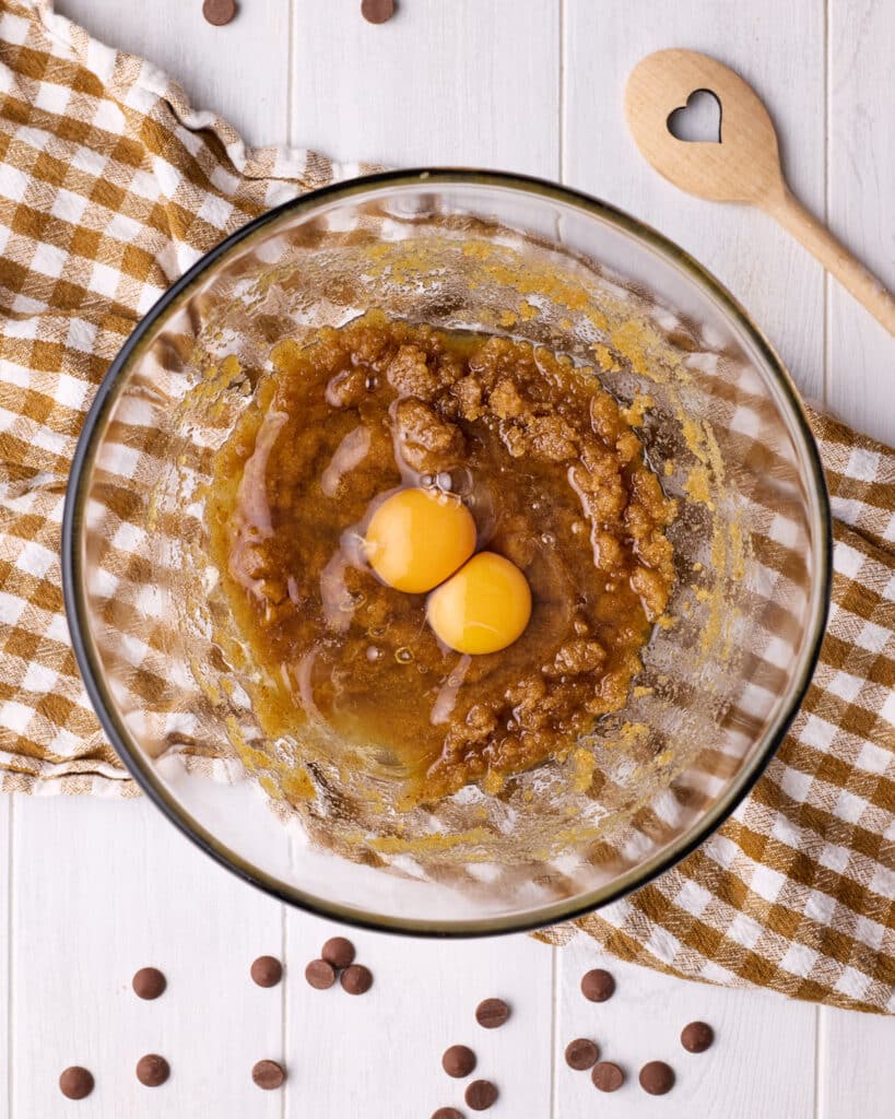 Brown butter mixed with sugar and eggs in a glass bowl to make brown butter cookies. 