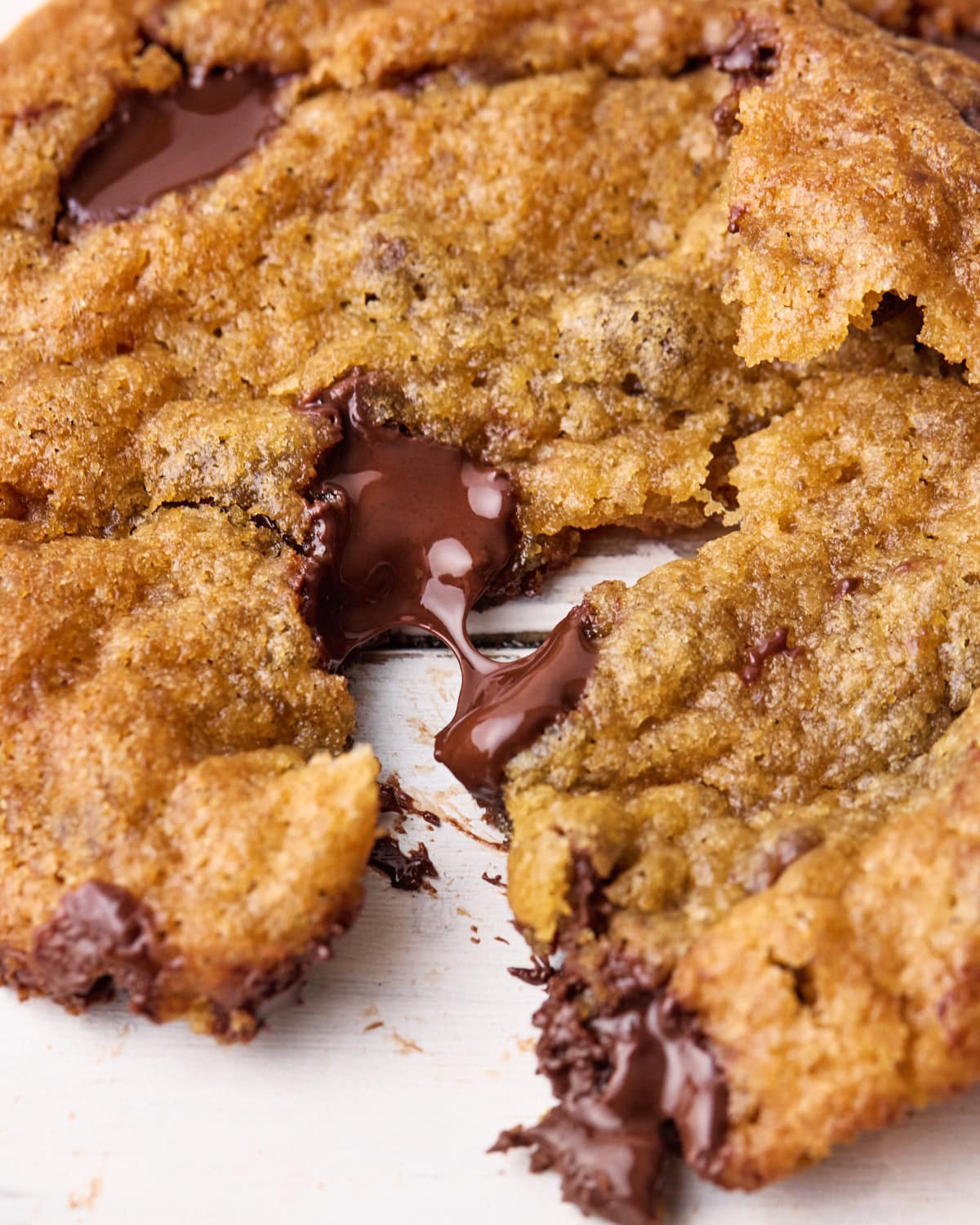 Close up of a brown butter chocolate chip cookie pulled slightly apart to show the melty chocolate chip.