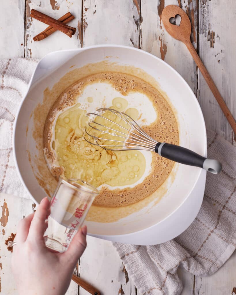 Adding wet ingredients to muffin batter to make cinnamon roll muffins.