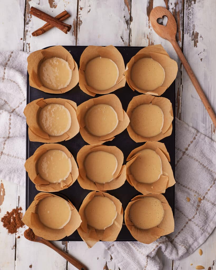 Process shots of making cinnamon roll muffins - scooping batter into muffin liners.
