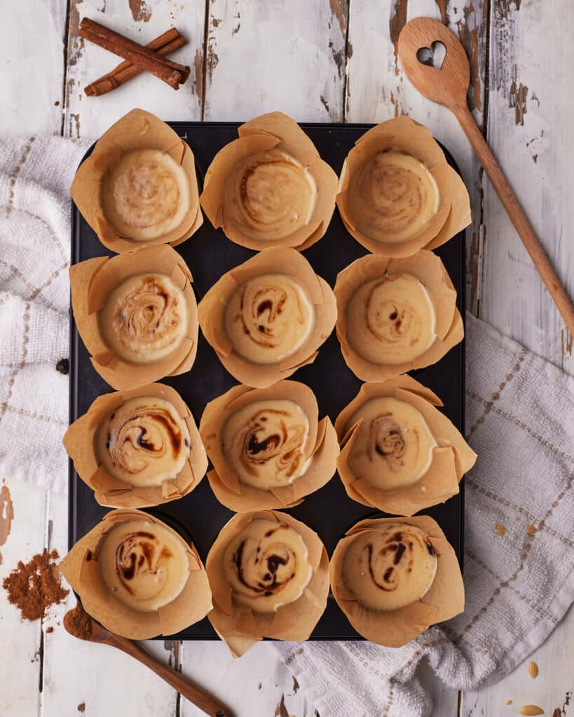Process shots of making cinnamon roll muffins - scooping batter into muffin liners.