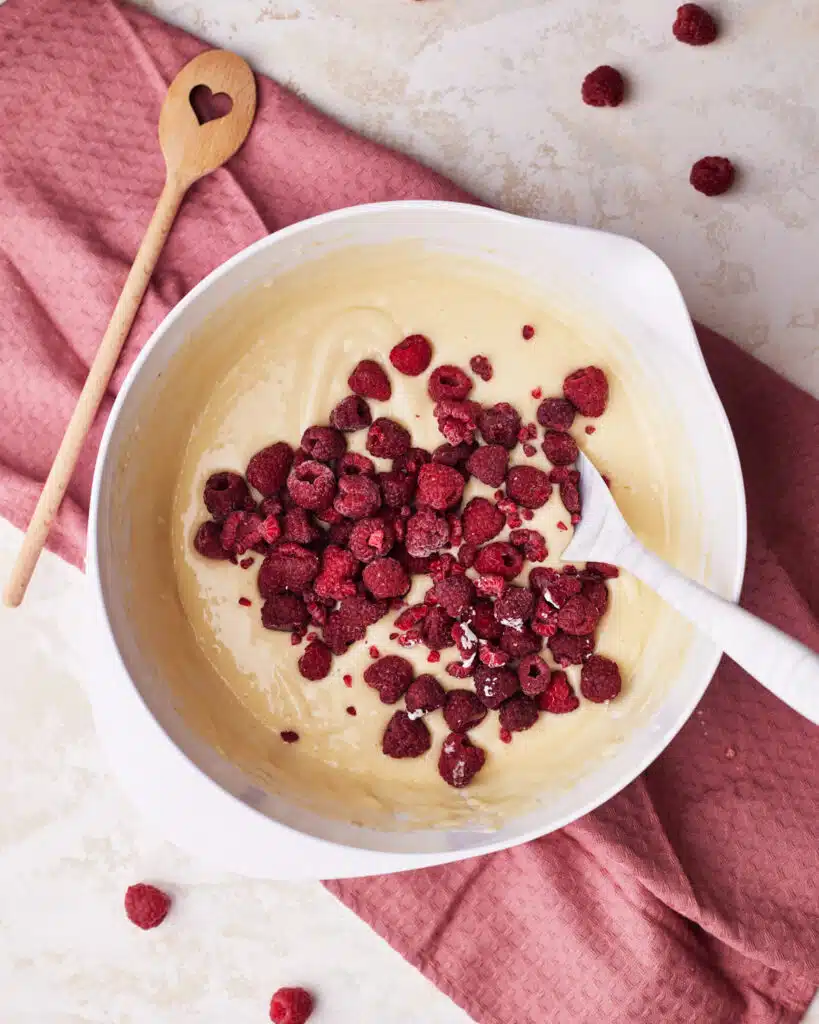 folding raspberries into raspberry muffin batter.