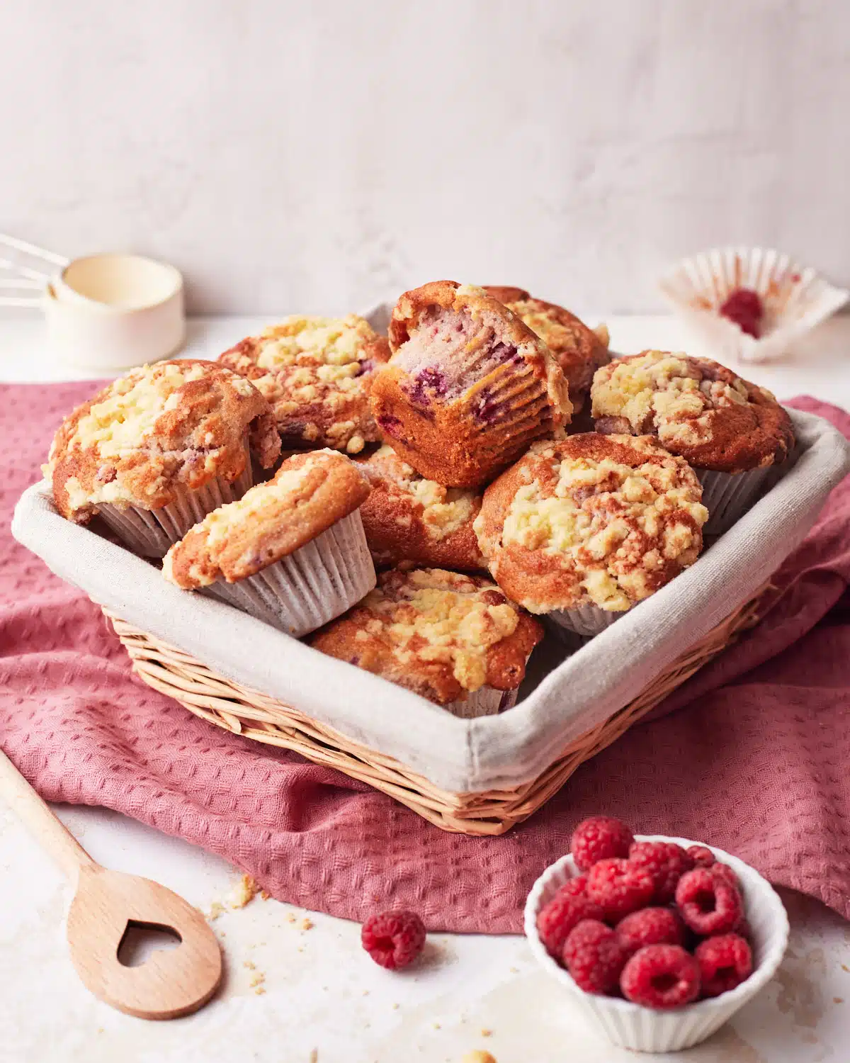 Basket full of raspberry muffins with crumb topping. 