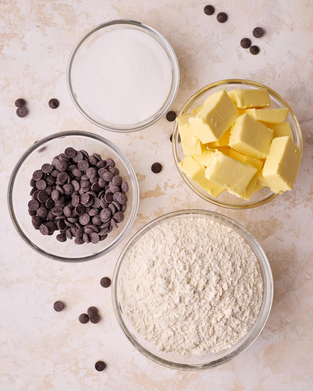 Ingredients to make chocolate chip shortbread cookies - sugar, butter, flour, and chocolate chips. 