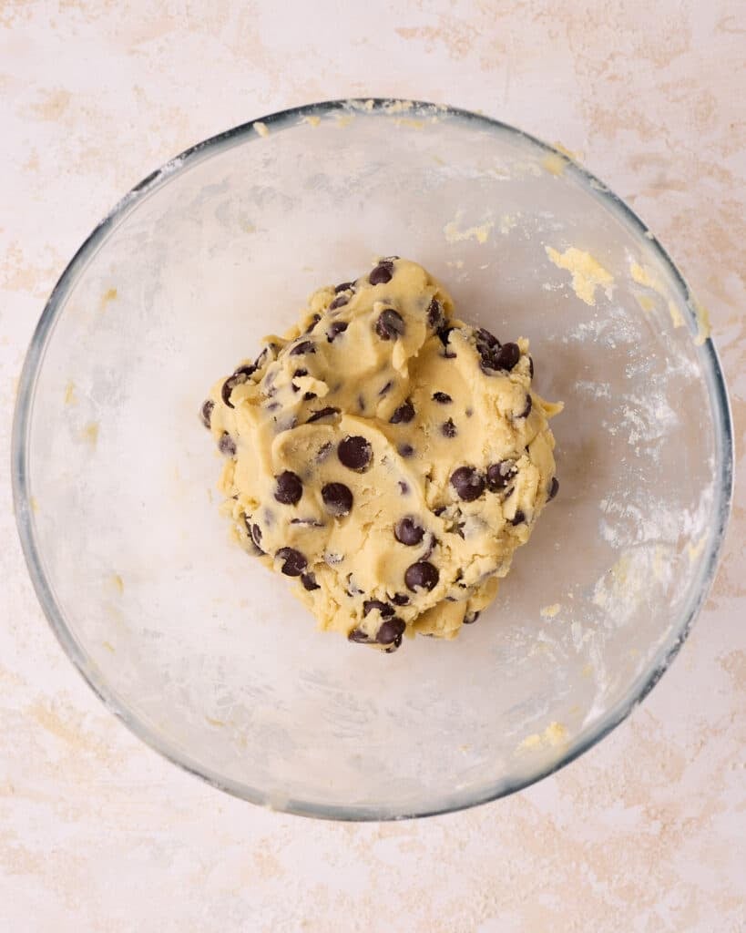 Adding chocolate chips to shortbread dough to make chocolate chip shortbread cookies.