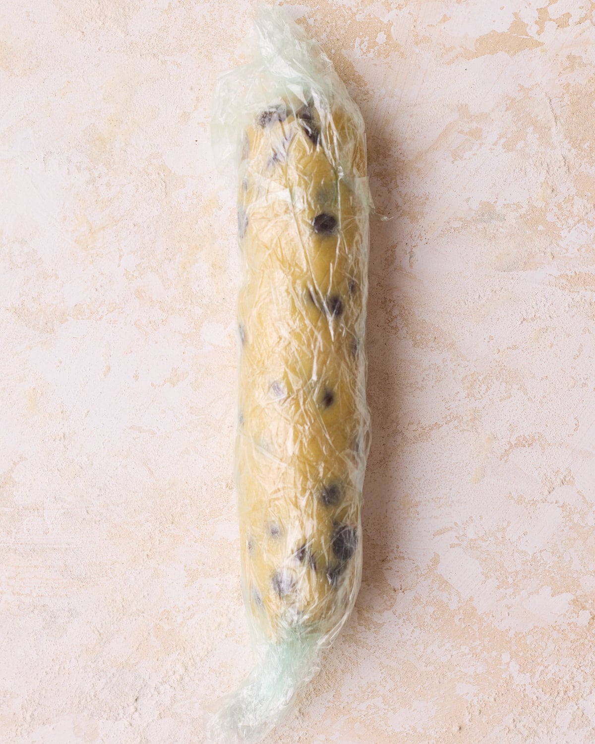 A log of shortbread dough that has been rolled out and wrapped in plastic wrap for the slice and bake method of making shortbread cookies.