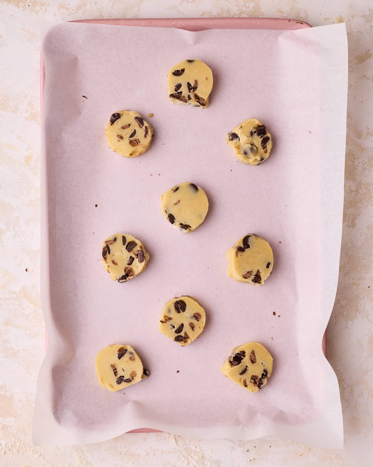 Chocolate chip shortbread cookie rounds on a baking sheet, ready to be baked.