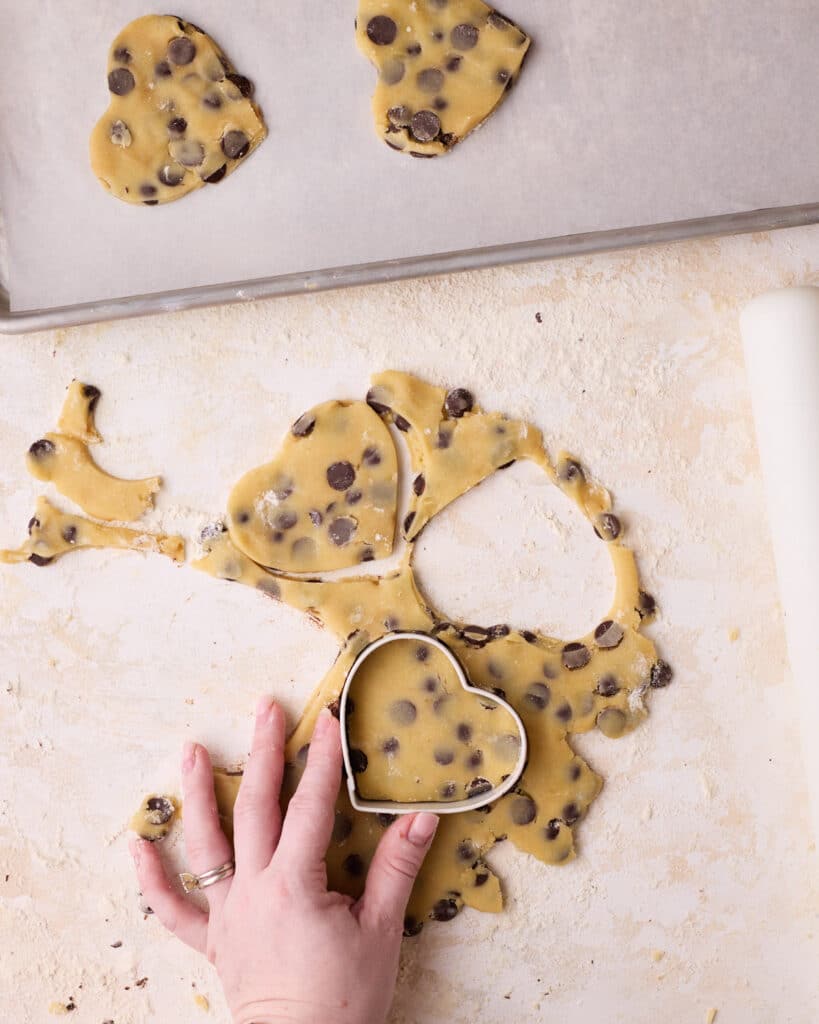 Cutting out heart shapes form rolled out chocolate chip shortbread cookie dough.
