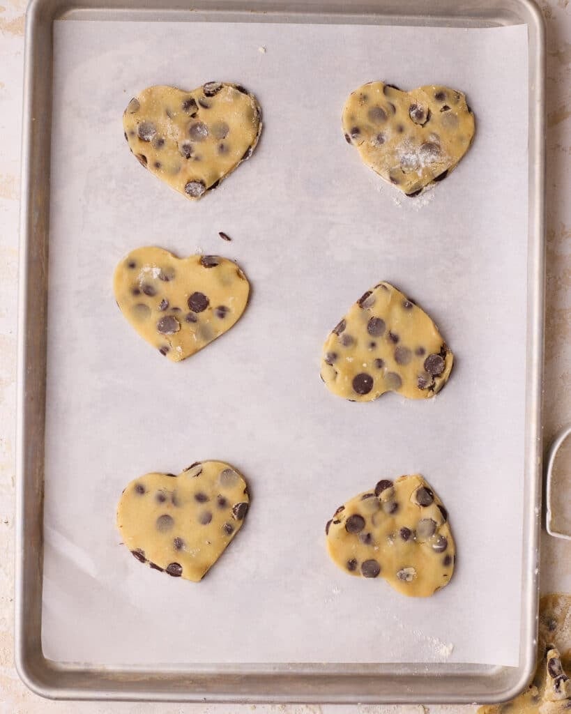 Cutout chocolate chip shortbread cookies on a baking sheet, ready to be baked.