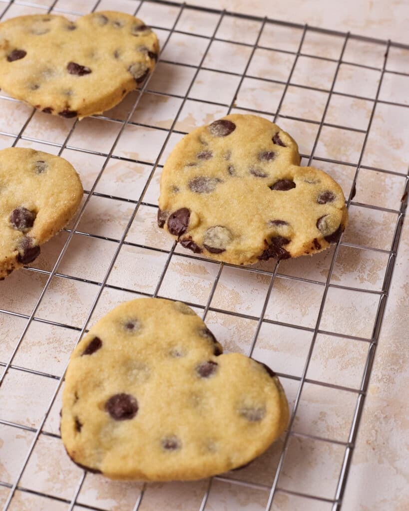 Heart shaped chocolate chip shortbread cookie cutouts on a cooling rack.