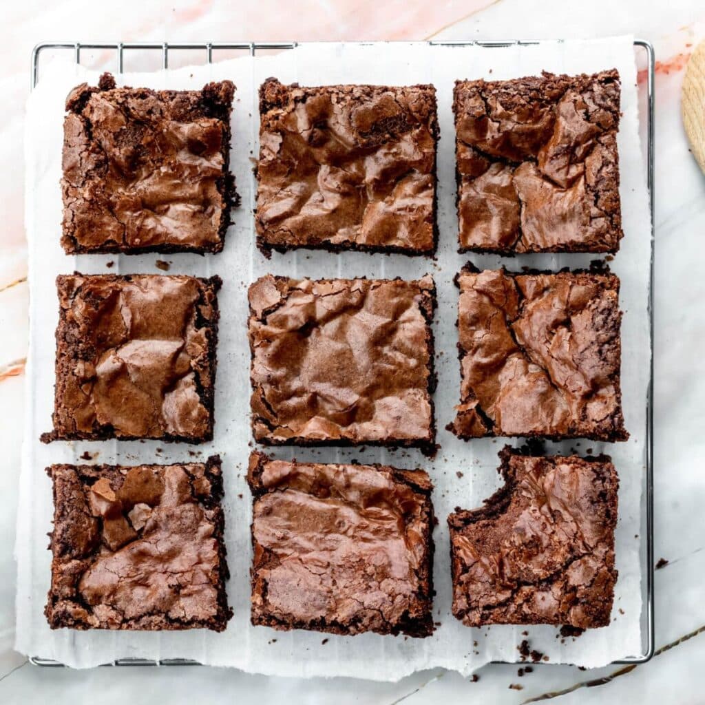 Ultimate chocolate brownies cut into squares spaced evenly apart, one brownie has a bite taken out of it.