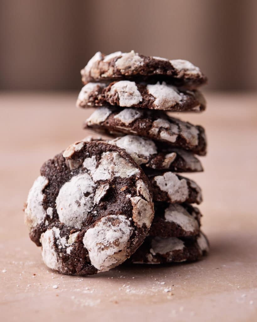 Stack of chocolate crinkle cookies with one cookie leaning to the side.