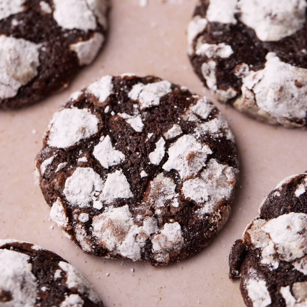 Overhead shot of a chocolate crinkle cookie with powdered sugar coating revealing a gooey center.