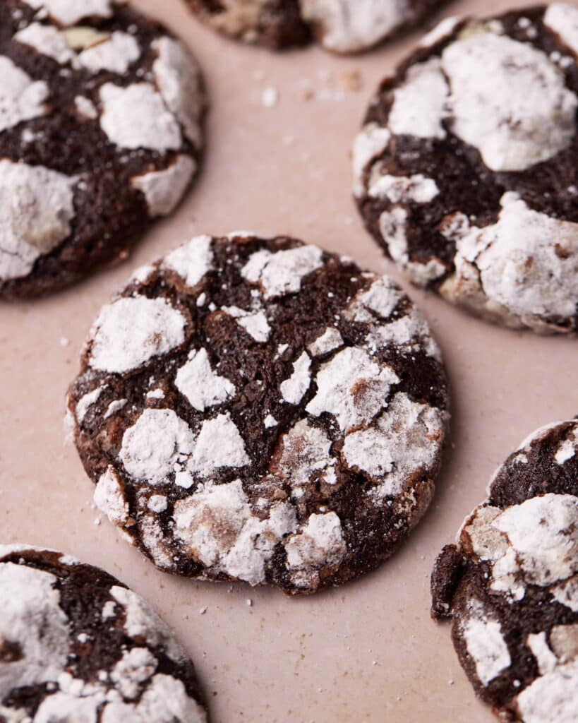 Overhead shot of a chocolate crinkle cookie with powdered sugar coating revealing a gooey center.