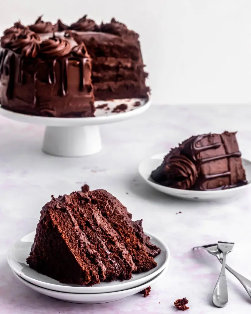 chocolate cake with two slices out of it on places