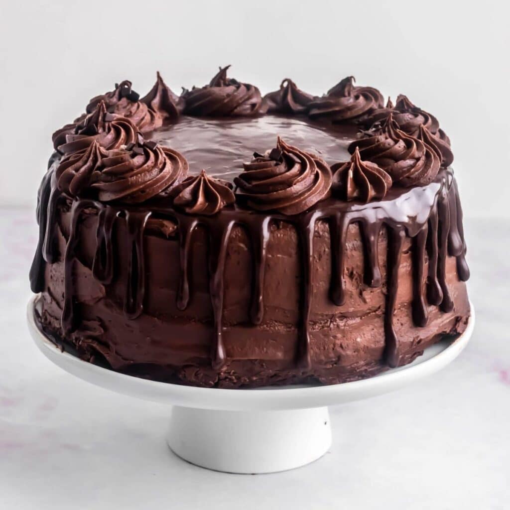 Death by chocolate cake with a chocolate drip on a raised display plate.