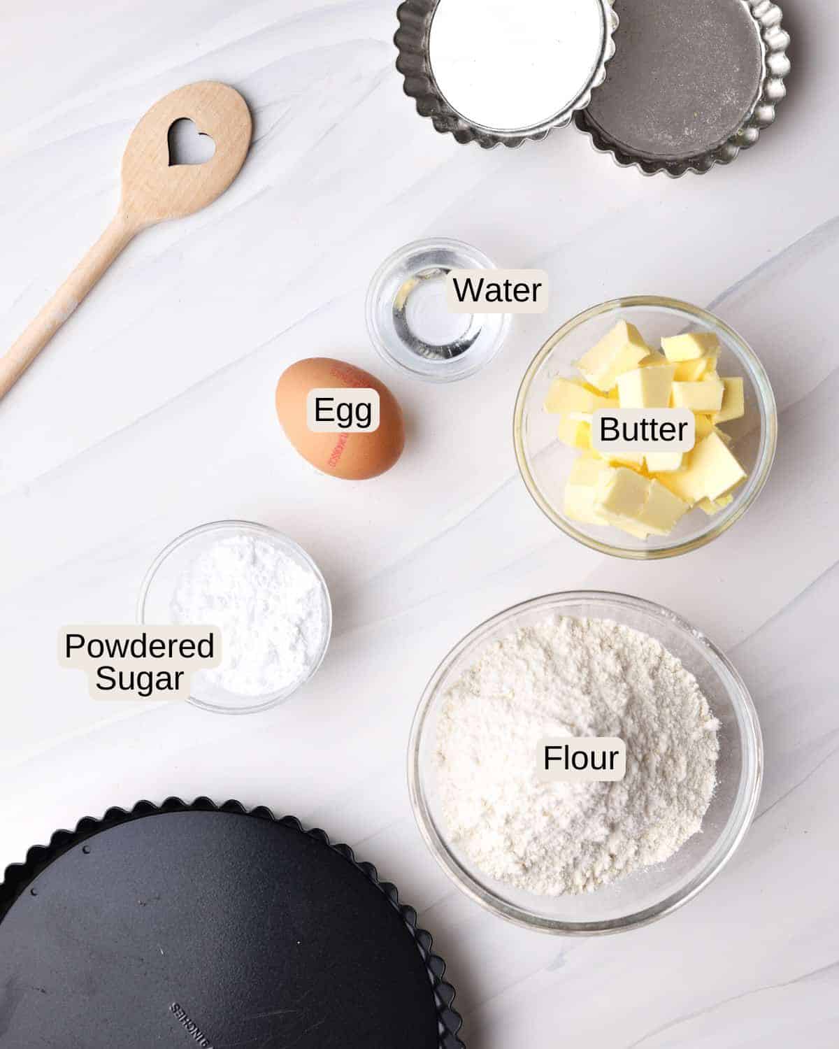 ingredients to make shortcrust pastry for tart shell - flour, sugar, egg yolk, butter, powdered sugar, water.