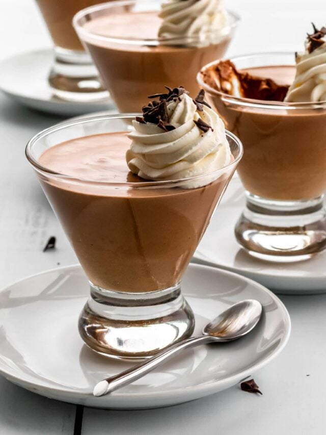 Chocolate mousse in glass serving dishes with whipped cream on top. 