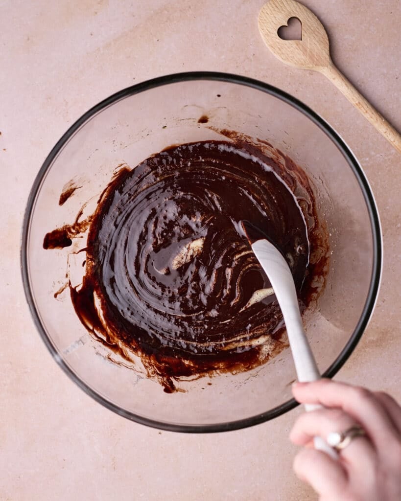 Mixing melted chocolate and butter into eggs and sugar to make batter for chocolate lava cakes.