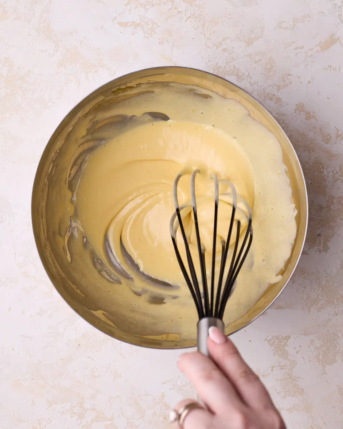 Whisking egg yolks and sugar until pale and thick to make mascarpone cream for tiramisu cake.