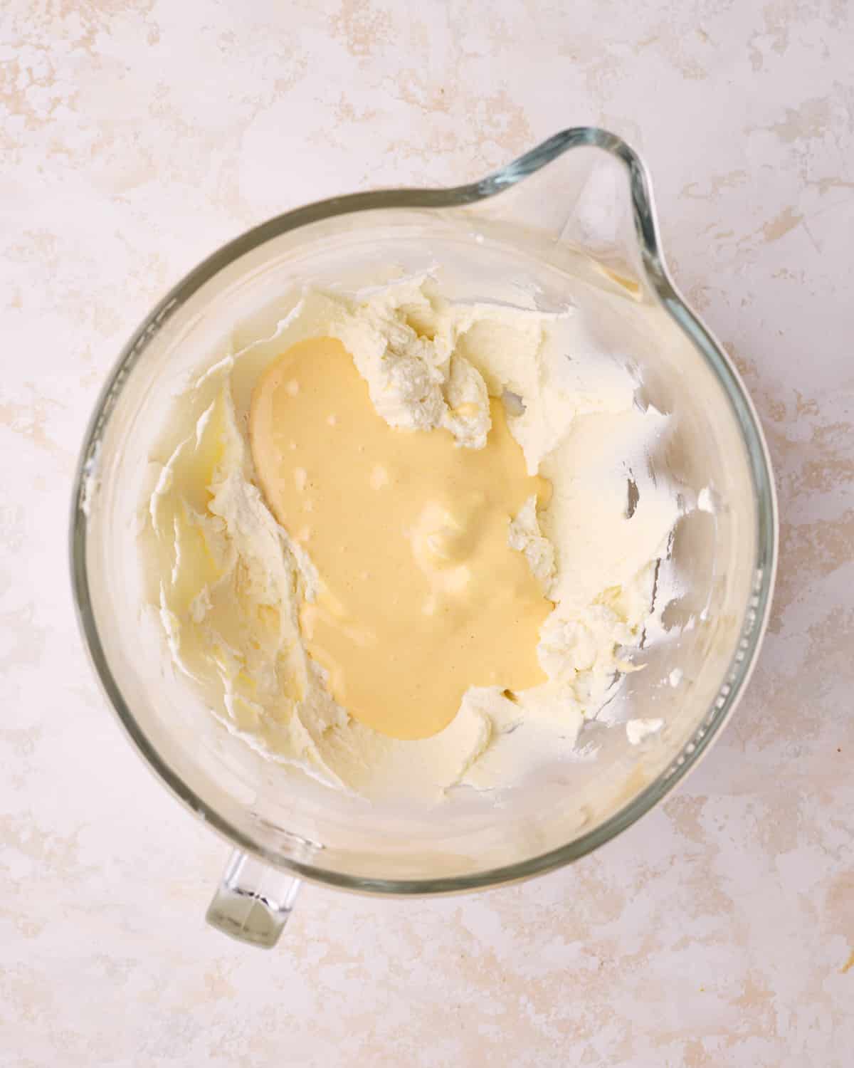 Adding egg yolk mixture to mascarpone to make filling for tiramisu cake.