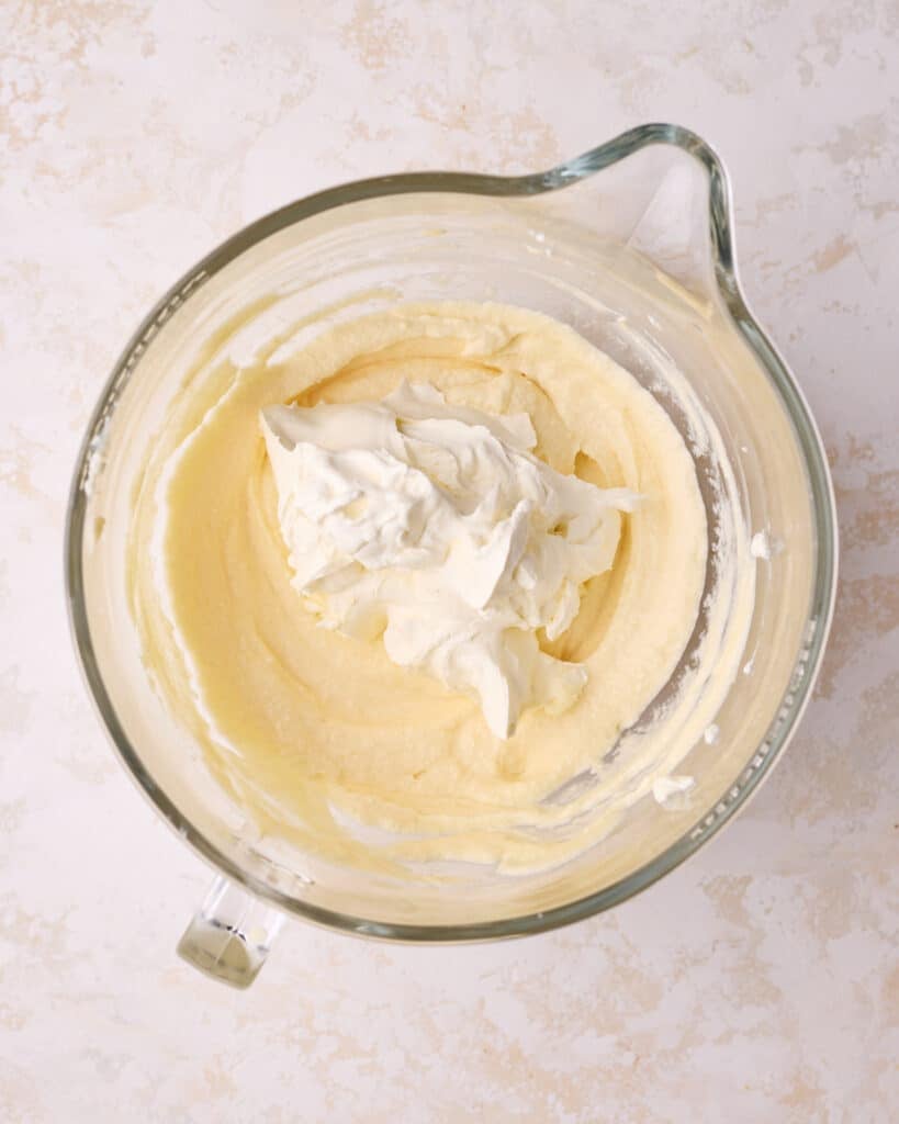 Folding whipped cream into mascarpone mixture to make filling for tiramisu cake. 