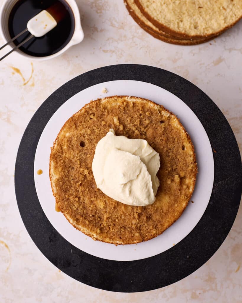 Adding mascarpone cream filling to a layer of soaked genoise sponge to make tiramisu cake. 