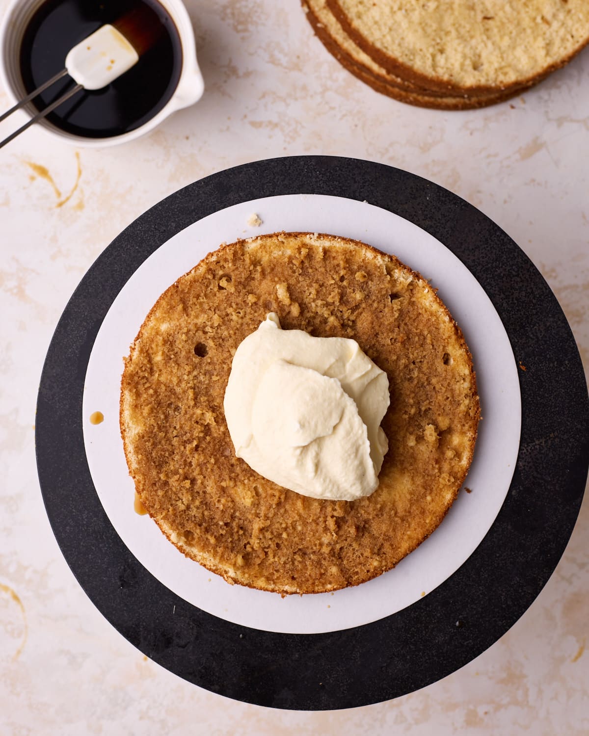 Adding mascarpone cream filling to a layer of soaked genoise sponge to make tiramisu cake.