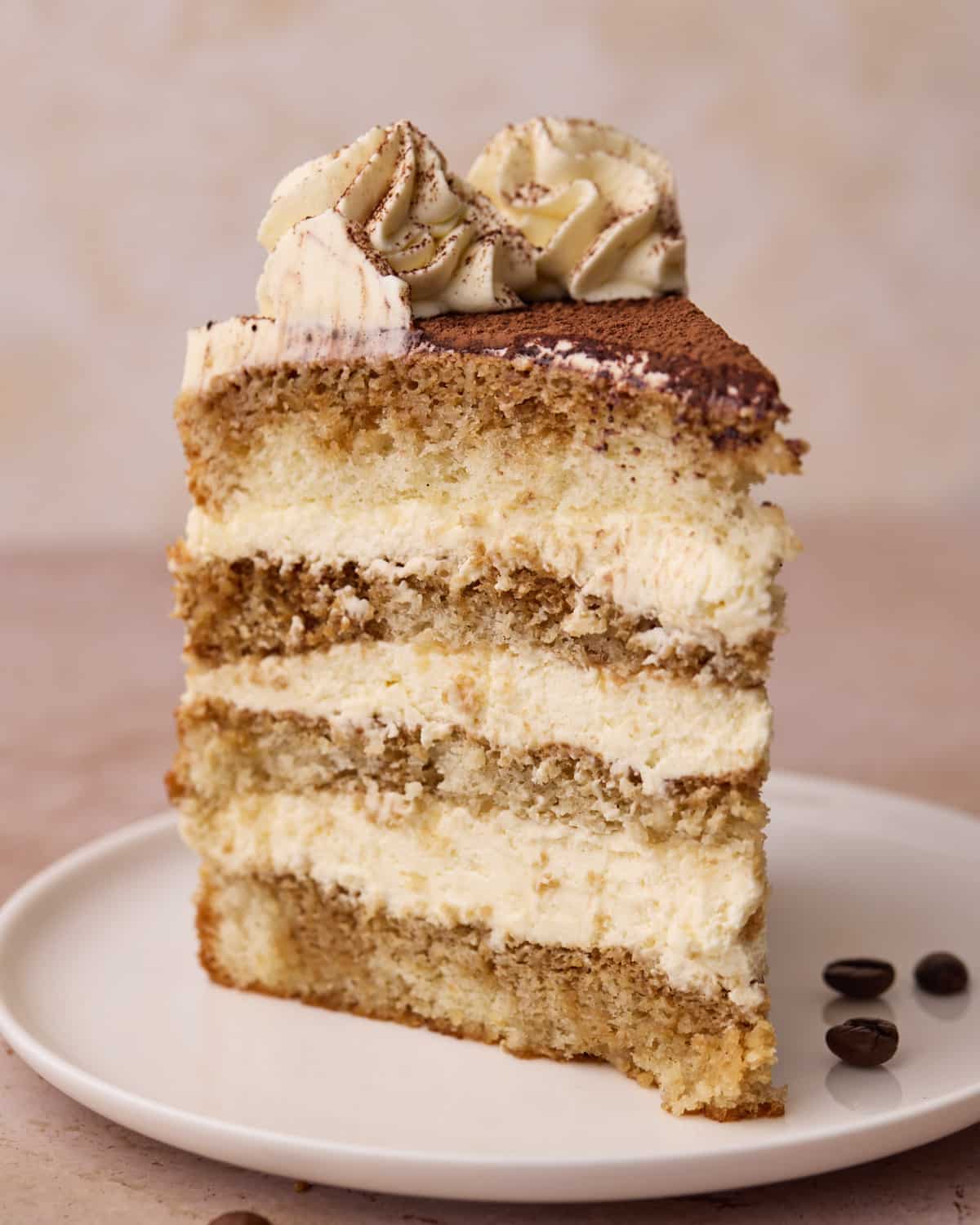 Close up of a slice of Tiramisu Cake with layers of soaked sponge cake and mascarpone cream.