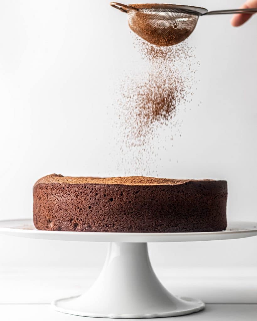 cocoa powder being dusted over cake