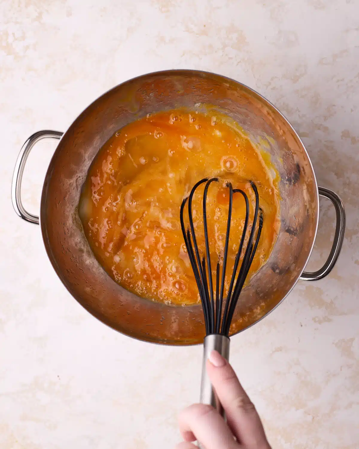 Whipping eggs and sugar over a double boiler to make genoise sponge cake.