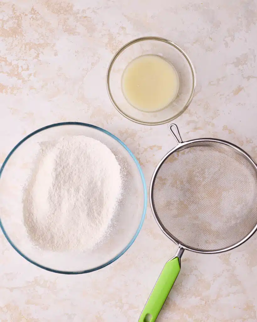 Flour being sifted and wet ingredients being mixed together to make genoise sponge cake. 