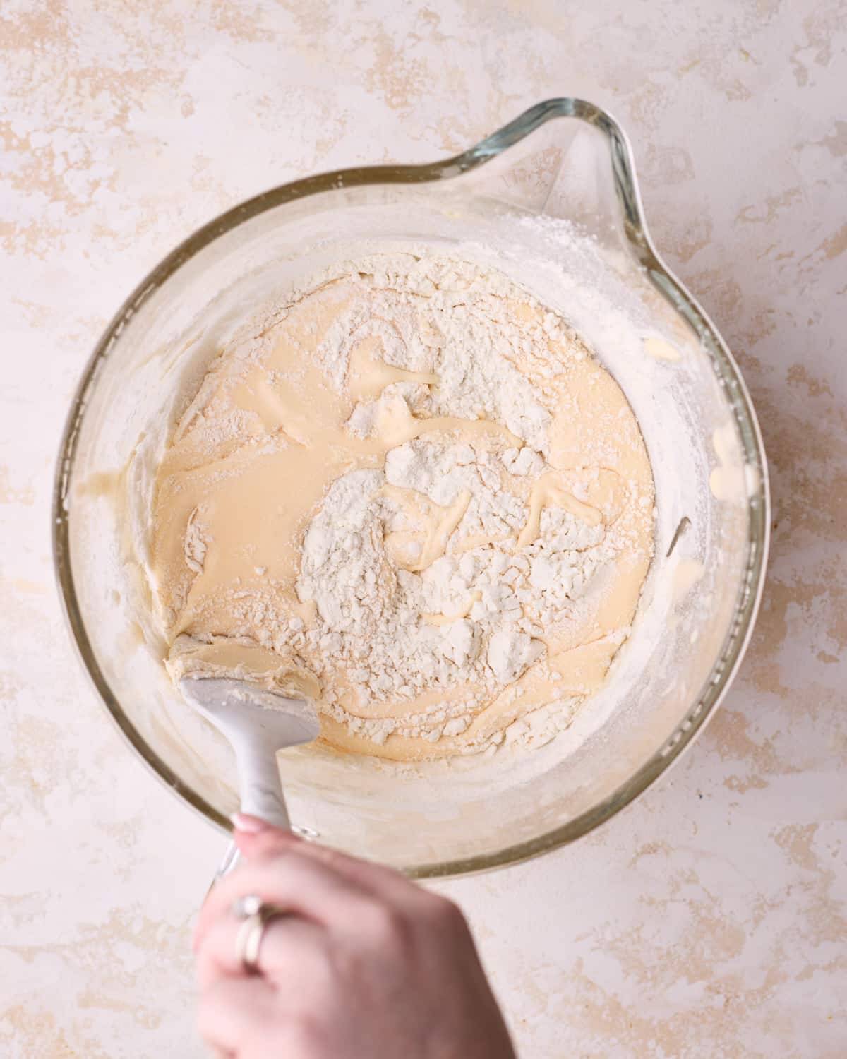 Folding flour into genoise cake batter very gently with a rubber spatula.