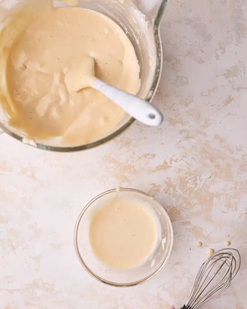 A big bowl of genoise cake batter with a small amount in a separate bowl to sacrifice the batter. 