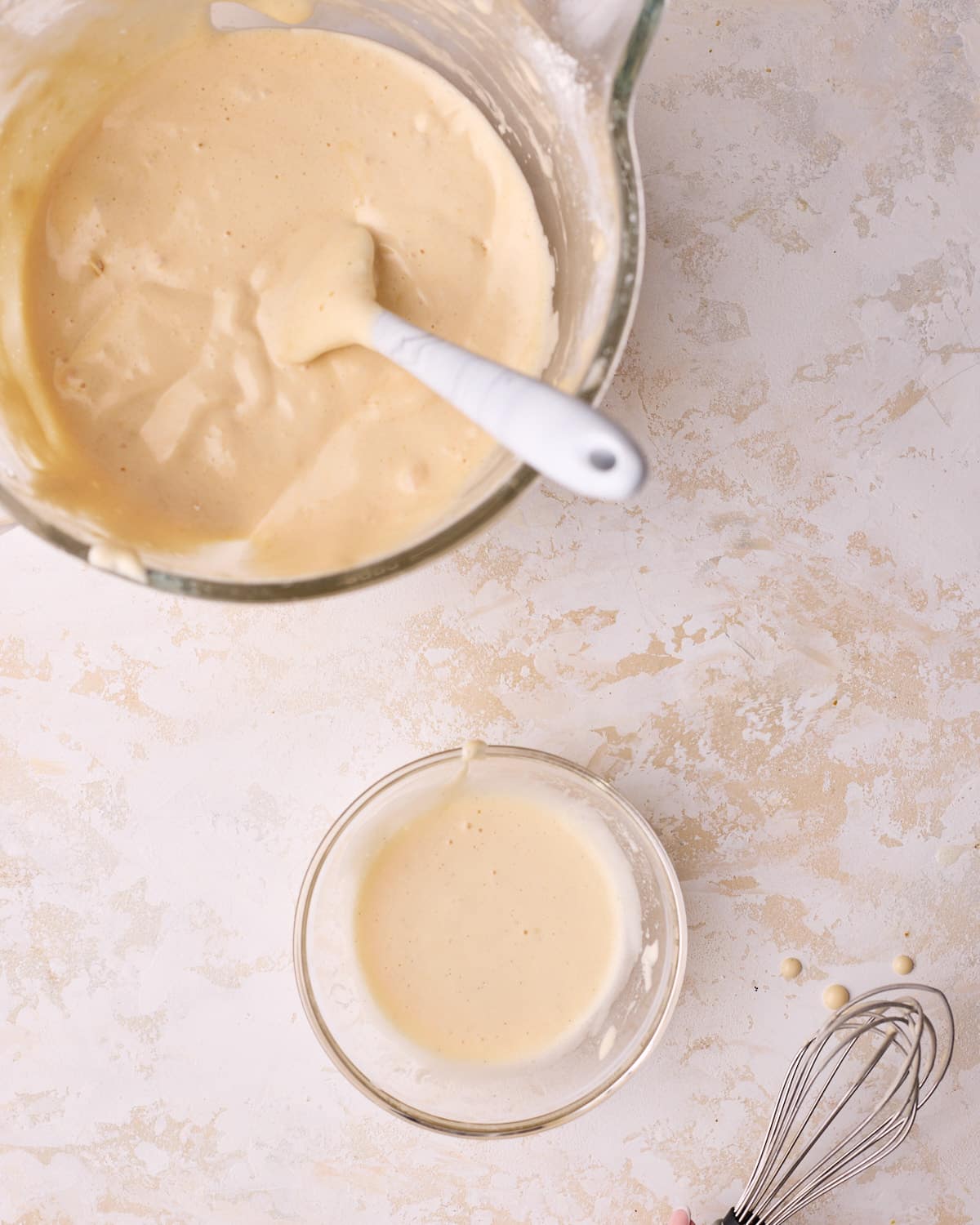 A big bowl of genoise cake batter with a small amount in a separate bowl to sacrifice the batter.