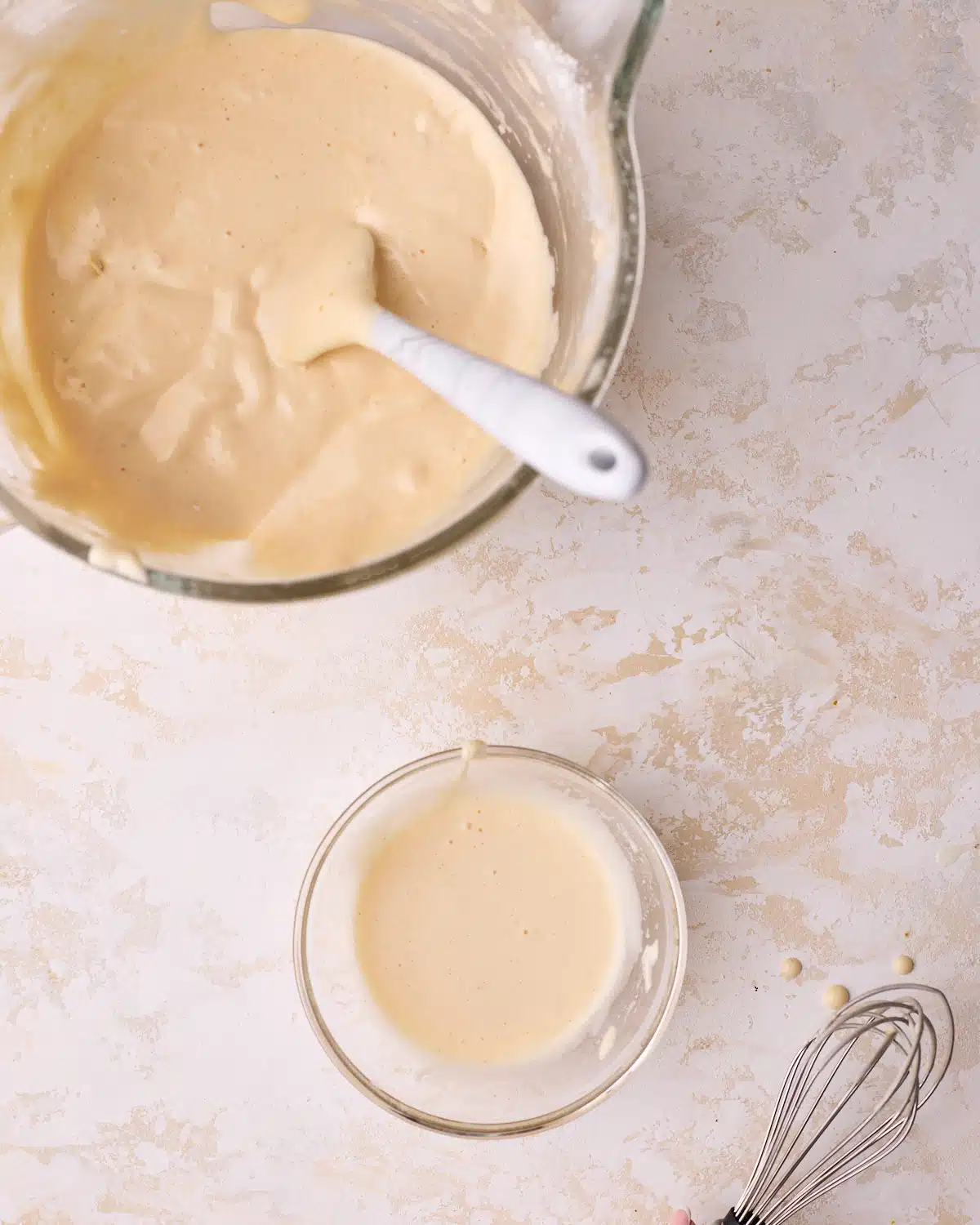 A big bowl of genoise cake batter with a small amount in a separate bowl to sacrifice the batter.