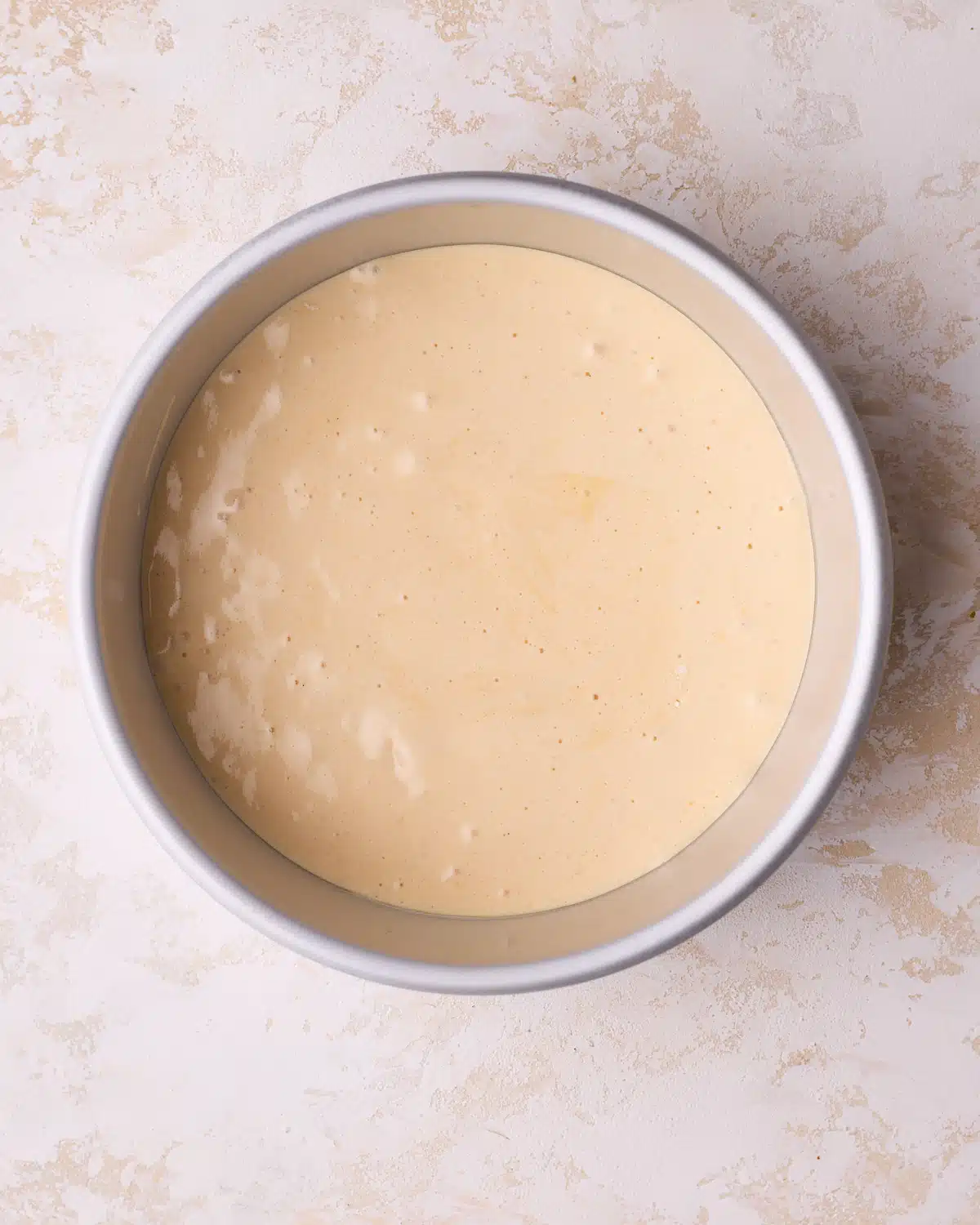 Genoise cake batter in a cake pan, ready to be baked.