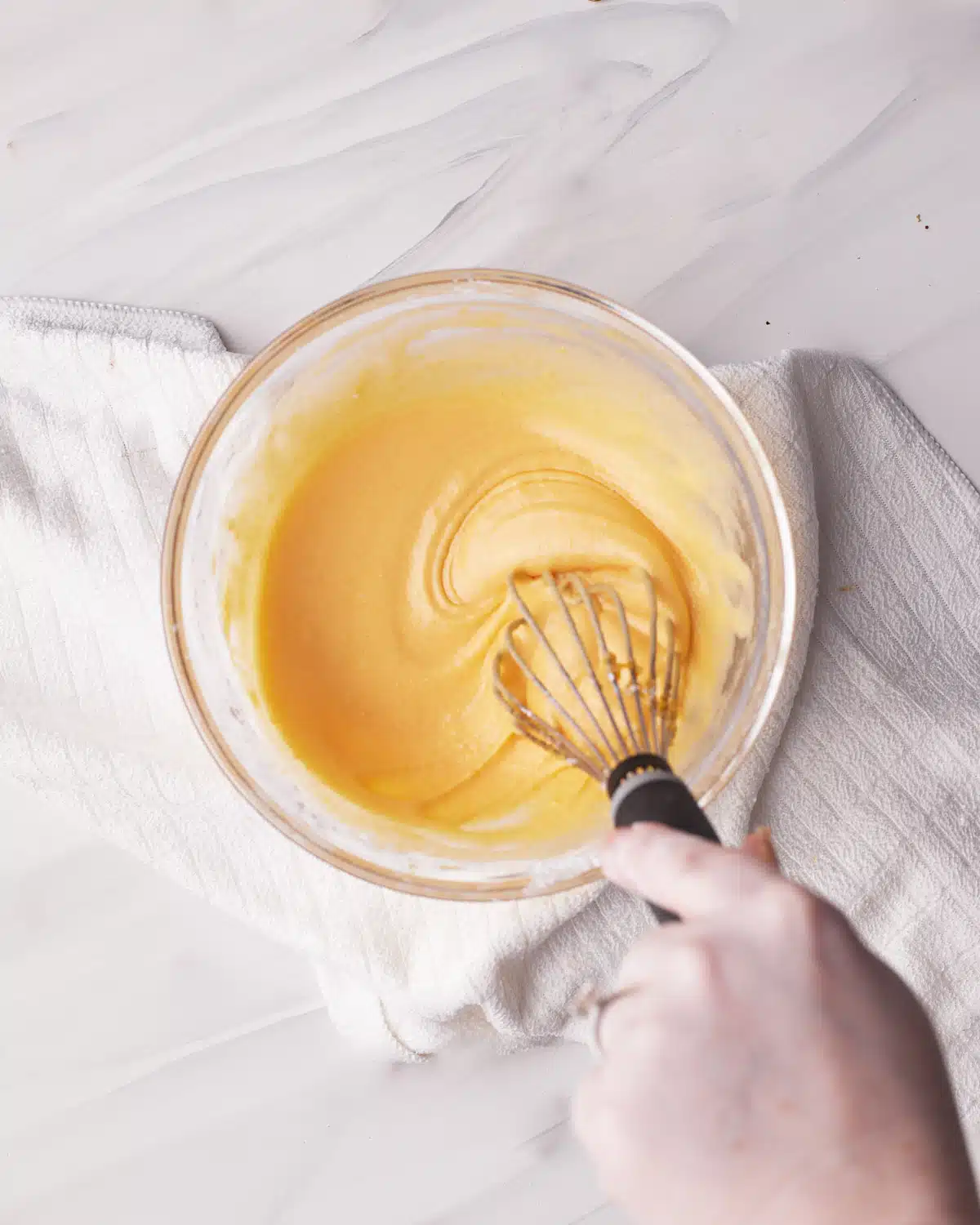 Whisking egg yolks with flour, corn starch and sugar to make custard filling for cake. 