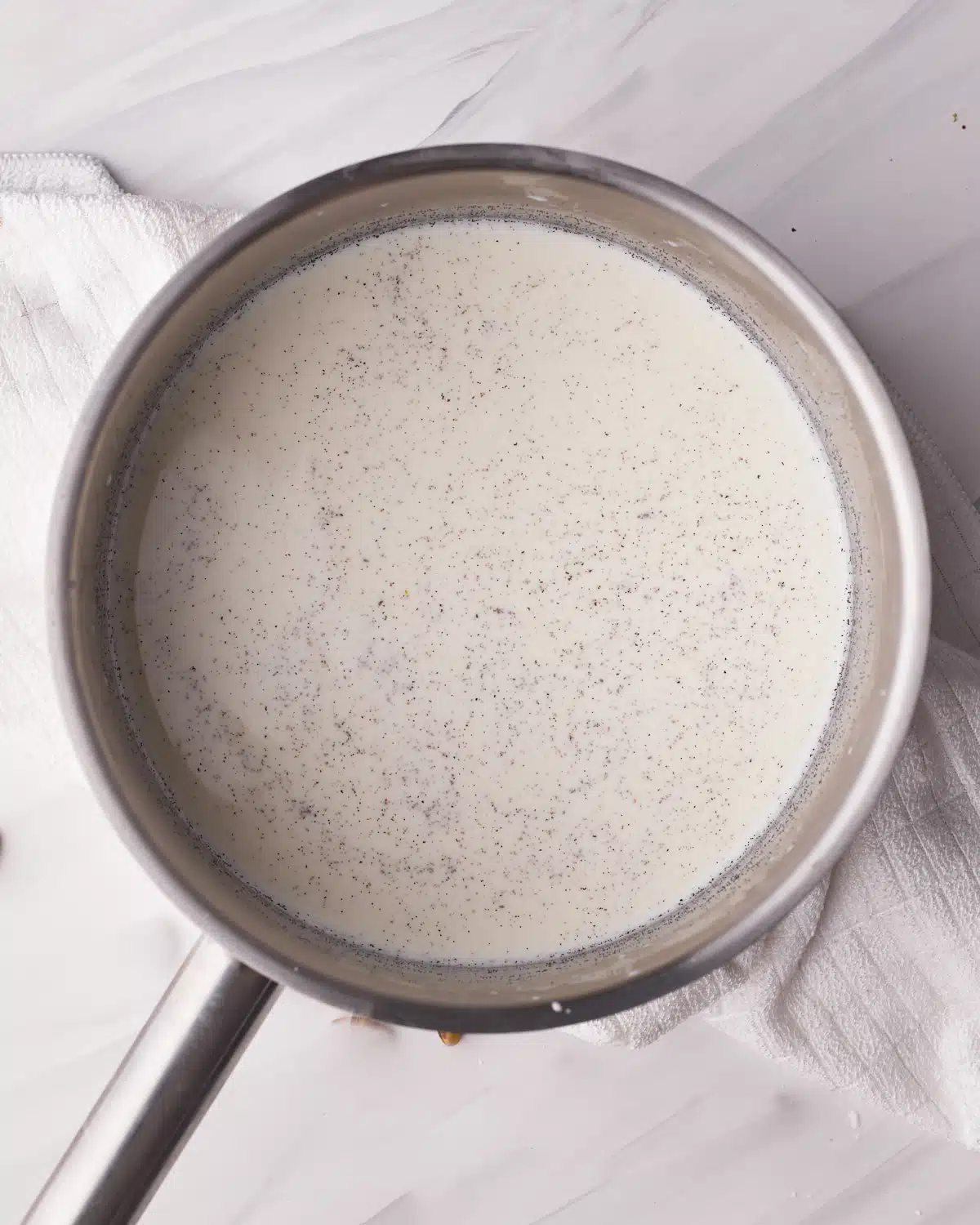 Milk and vanilla bean paste in a saucepan, ready to make custard. 