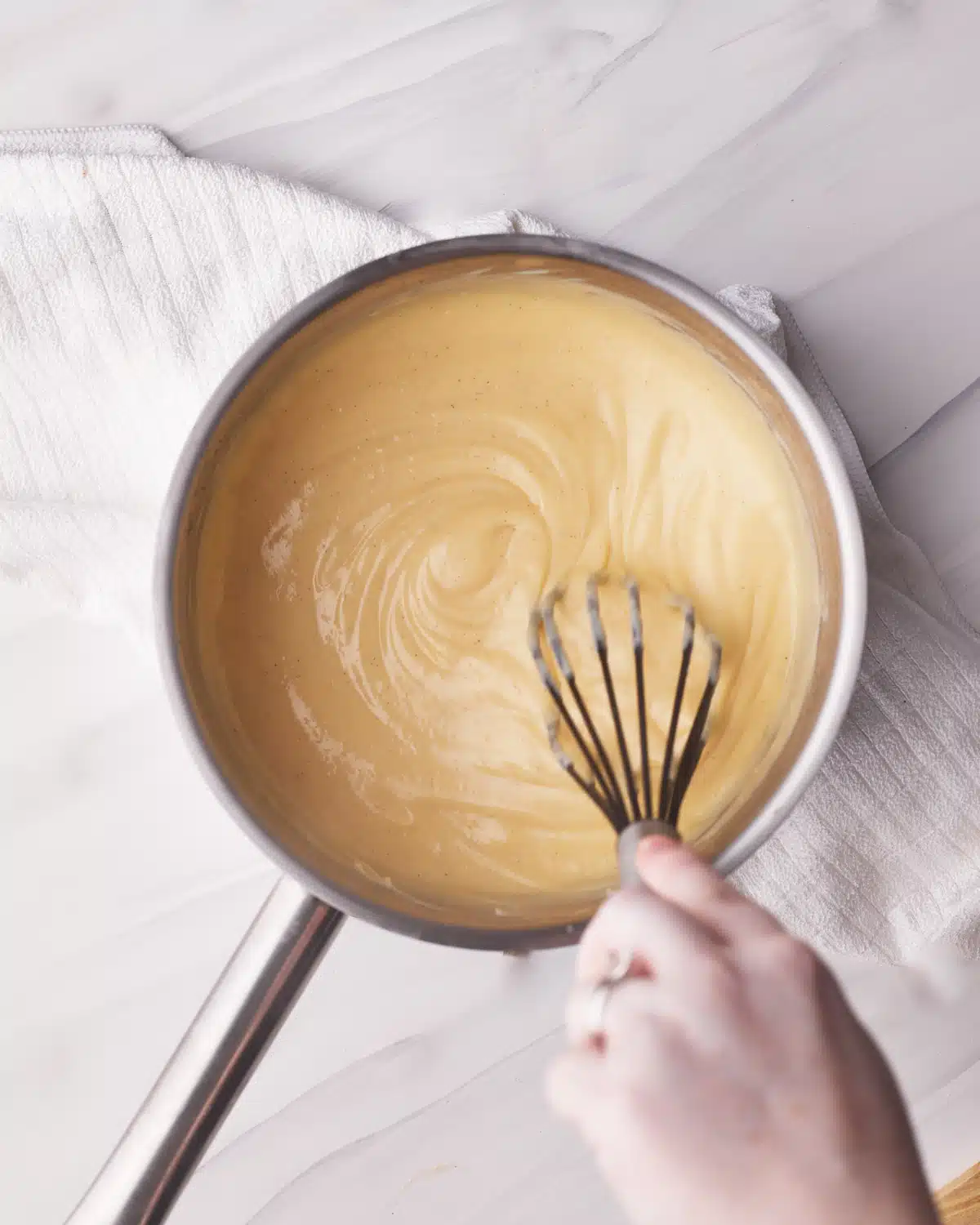 Whisking vanilla pastry cream (custard) in a saucepan. 