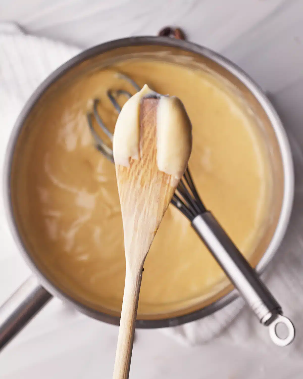 Testing if custard filling is ready by drawing a line in it on the back of a spoon. 