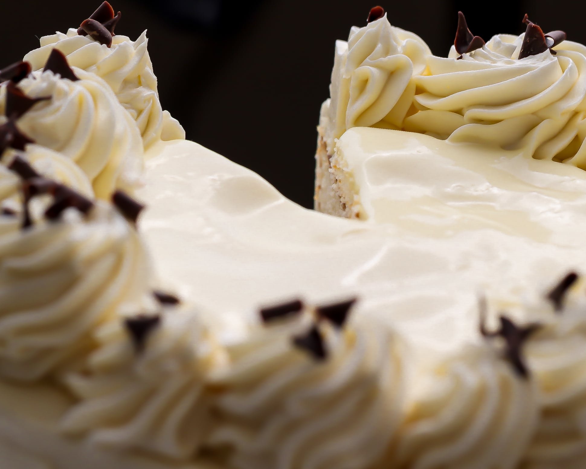Close up of German buttercream frosting on the top of custard cake, with a slice cut out of it.