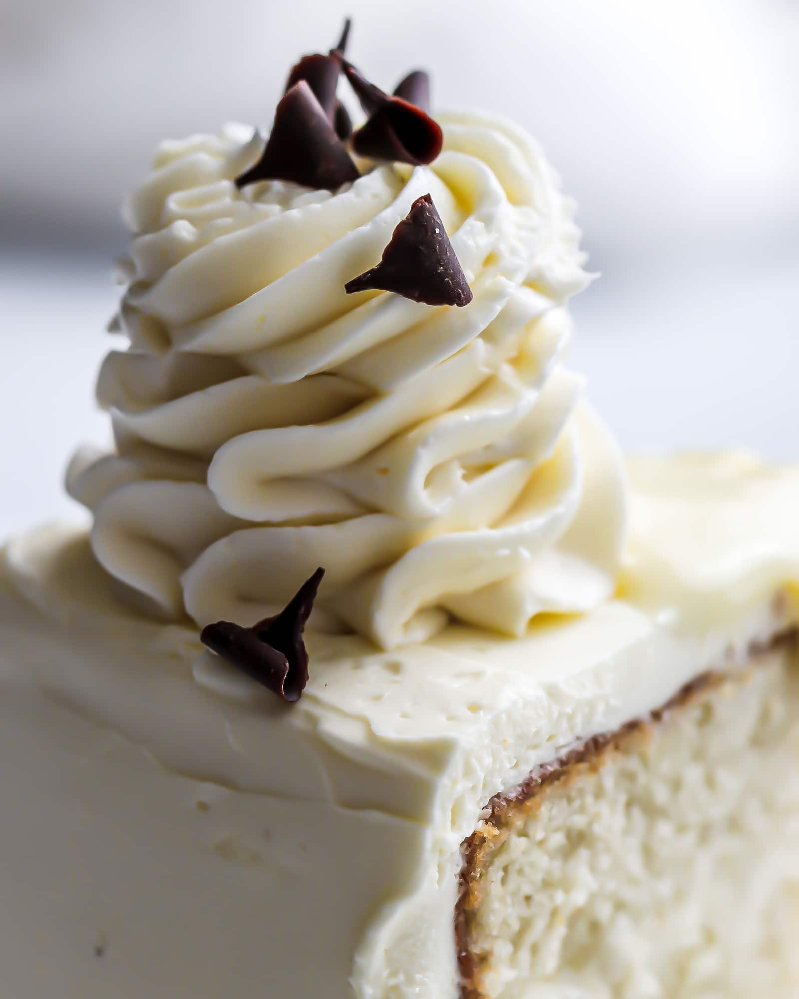 Close up of the custard buttercream piped tall into a swirl with chocolate shavings on top.