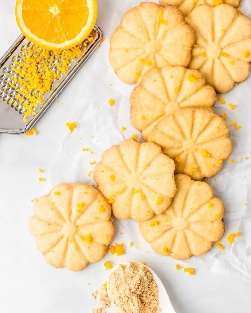 orange and ginger cookies in a pile with zester and orange