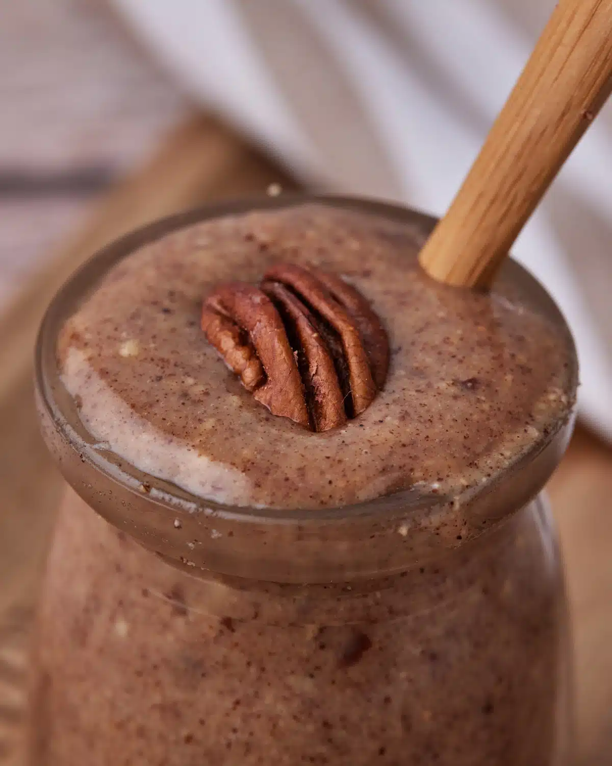pecan butter in a glass jar with a whole pecan on top. 