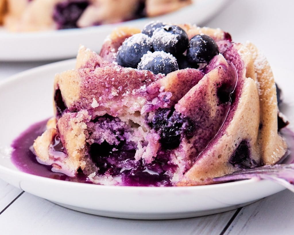 Mini blueberry bundt cake soaked in blueberry glaze with a bite out of it