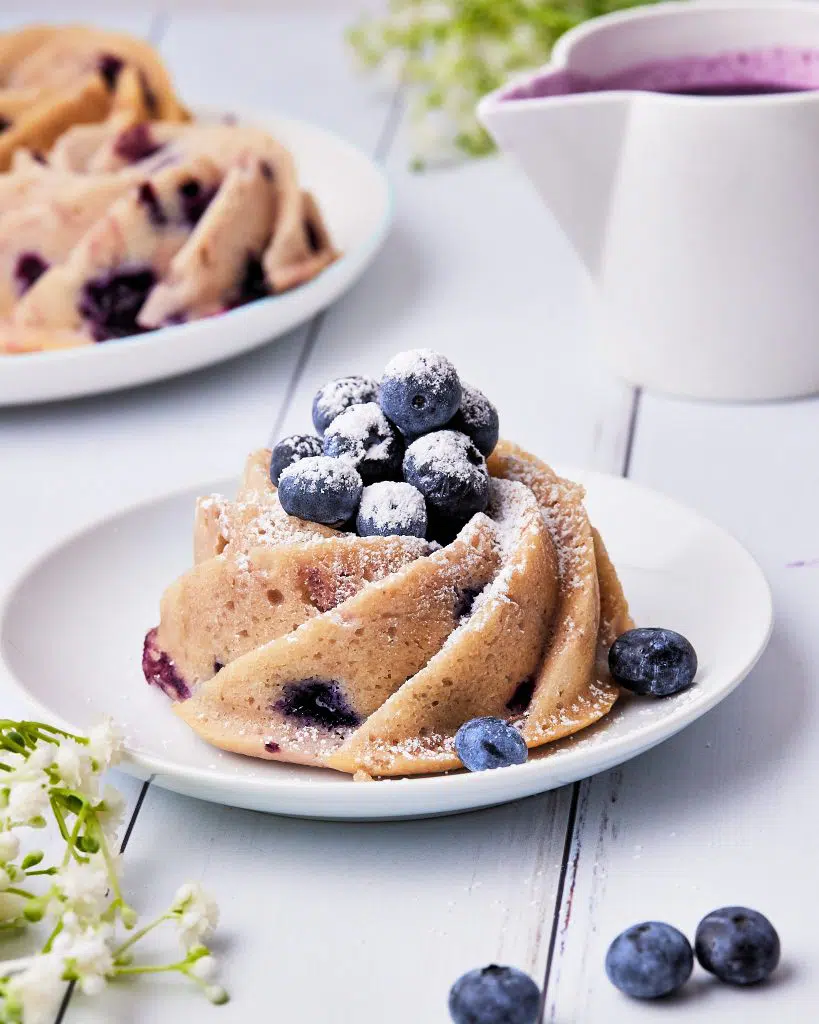 mini blueberry bundt cake with fresh blueberries on top and icing sugar