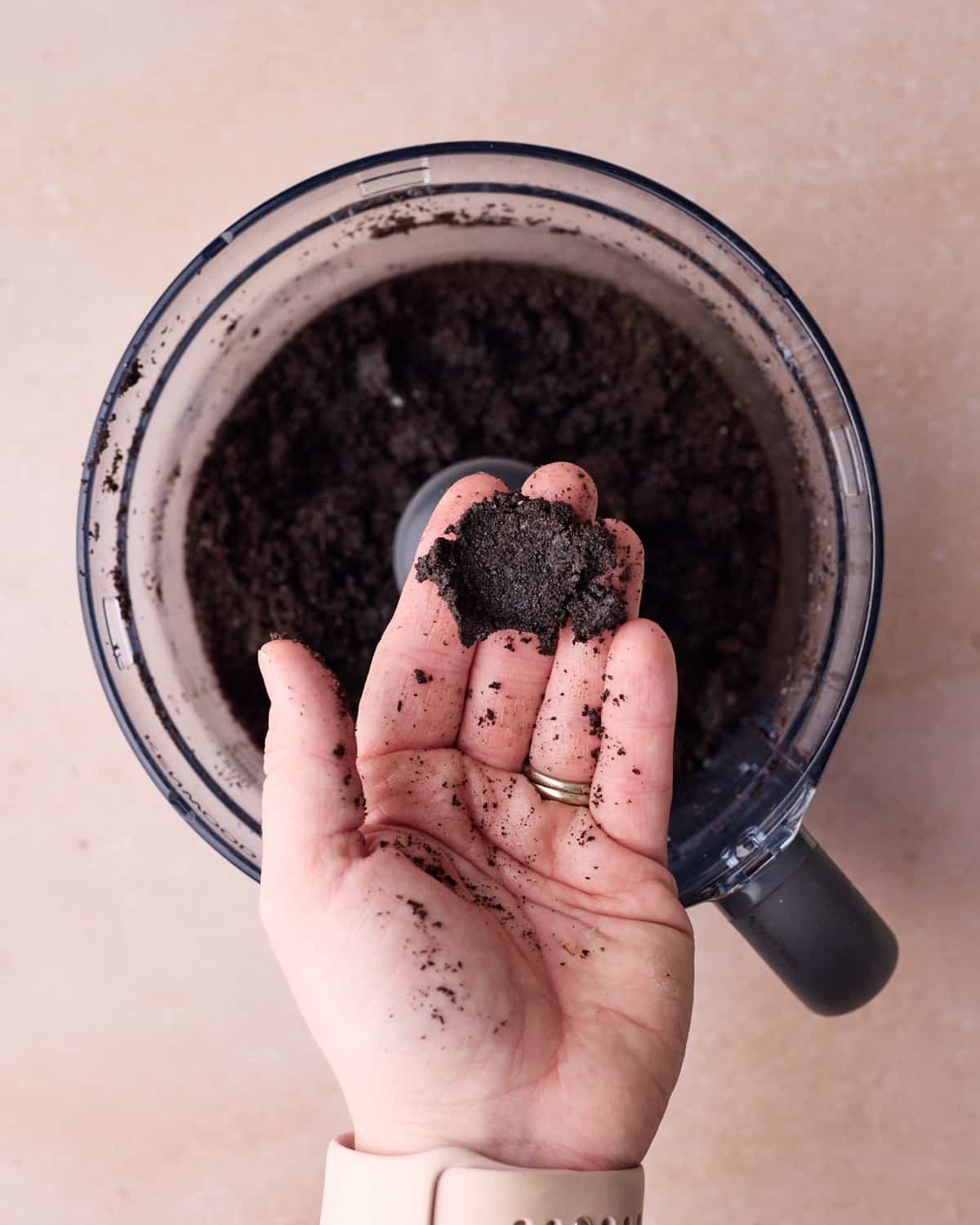 Oreo crumb crust mixture being squeezed to show that the correct consistency clumps together.