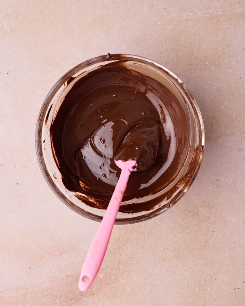 Dark chocolate melted in a glass bowl until smooth and shiny.