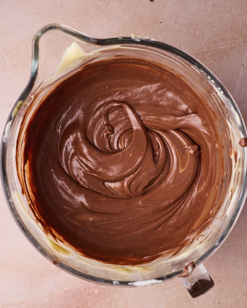 Chocolate cheesecake batter in a glass mixing bowl.